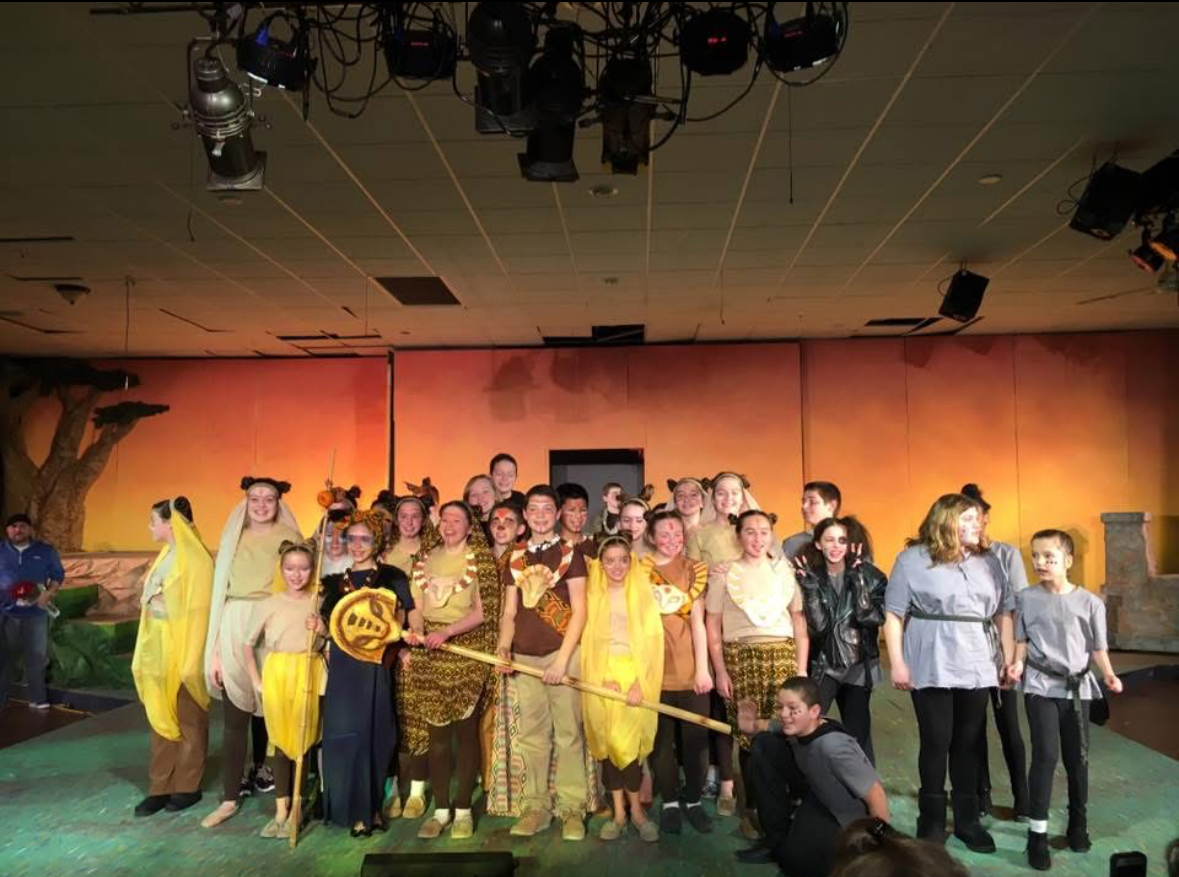 Student cast on stage after a sponsored school performance