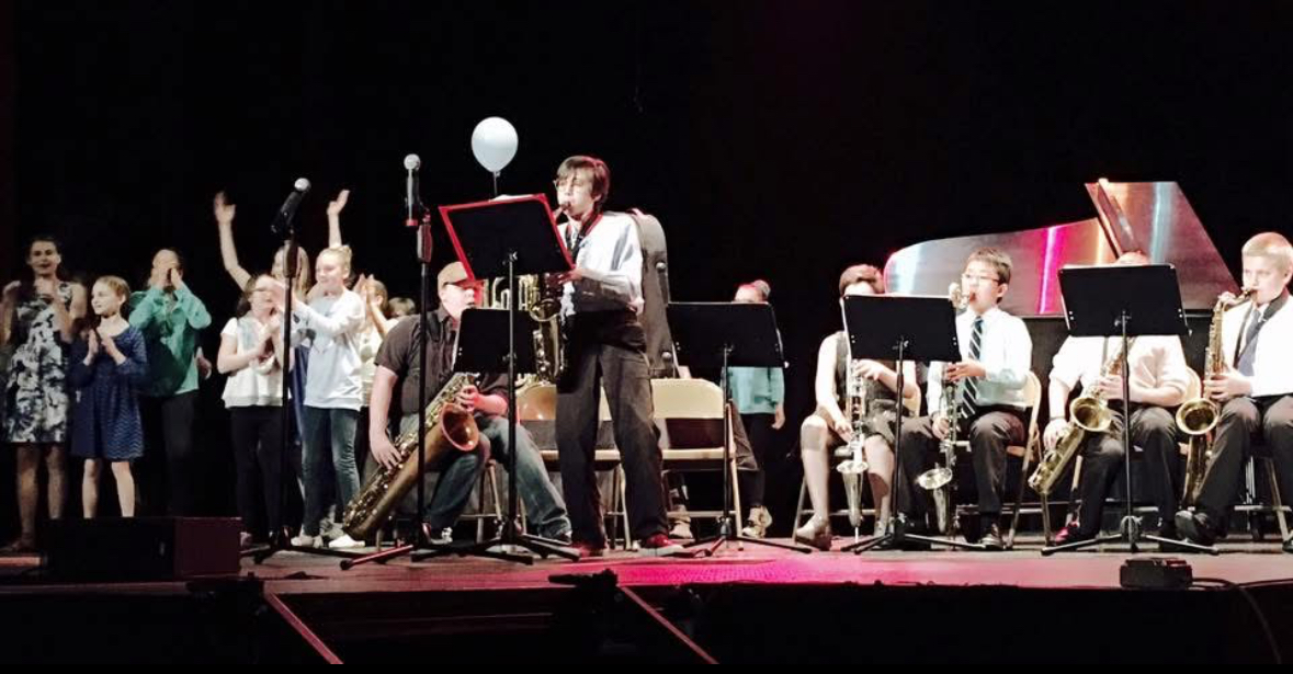 Students performing music on stage during a sponsored arts event